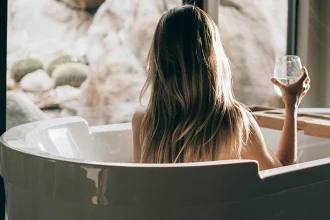Frau in Badewanne mit Glas Wein im Hotel Wellness